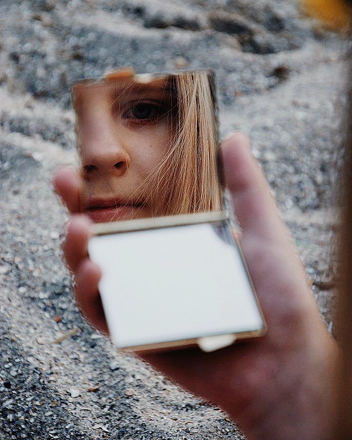 Face reflected in a small hand mirror