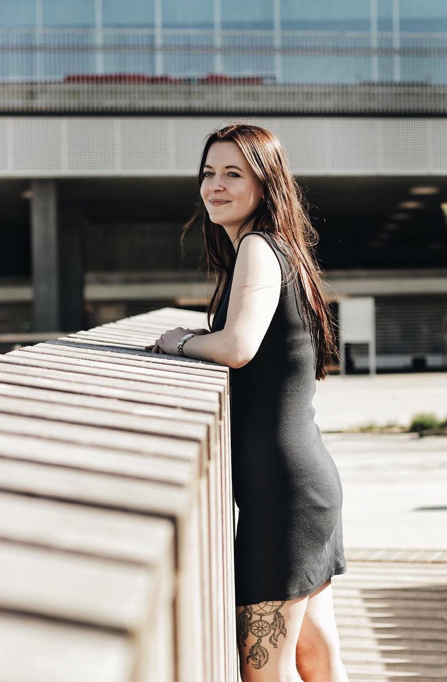 Woman in a grey dress leaning on a wooden railing
